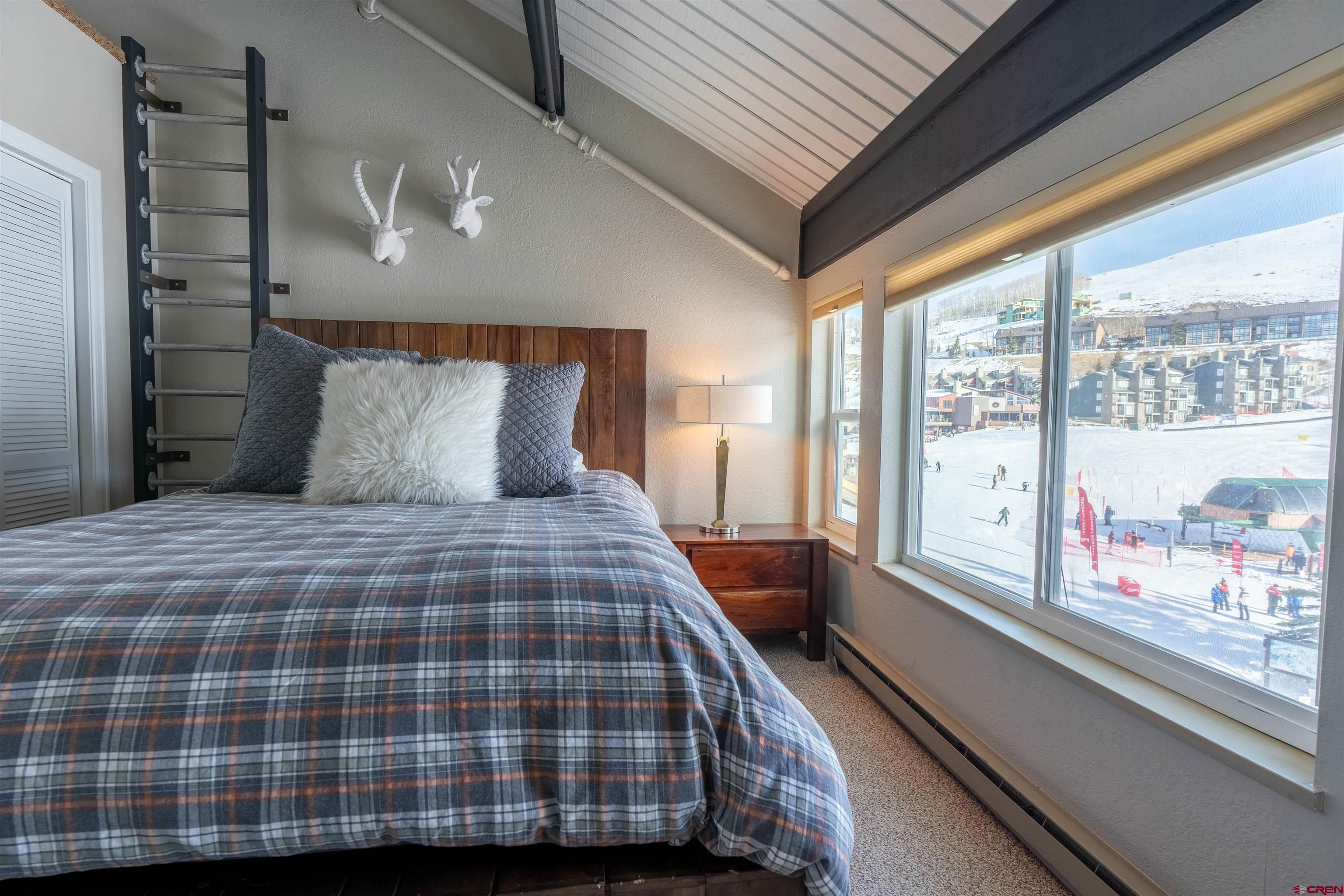 12 Snowmass Road, Unit 414 Crested Butte, CO 81225 - Photo 21 of 33 a bedroom with a large bed and a large window with balcony view