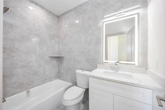 a bathroom with a granite countertop toilet a sink and a bathtub