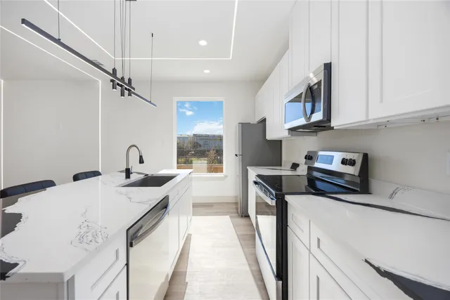 a kitchen with stainless steel appliances granite countertop a sink a stove and a refrigerator