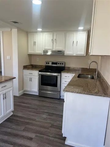 a kitchen with granite countertop wooden cabinets and a stove