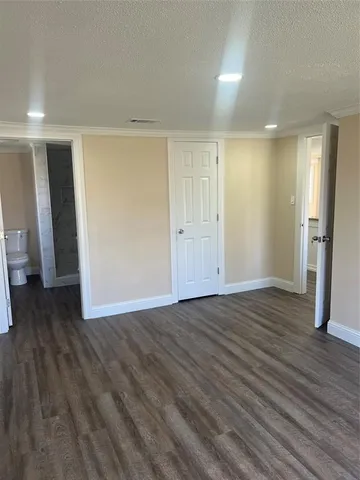 a view of an empty room with wooden floor and closet