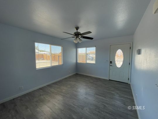 1224 South McCall Street Ridgecrest, CA 93555 - Photo 4 of 9 an empty room with wooden floor fan and windows