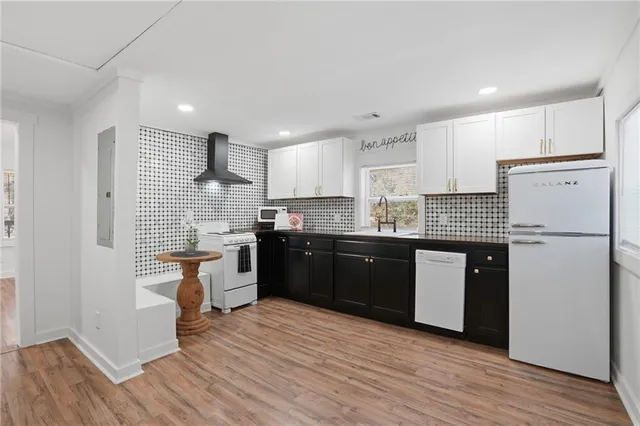 a kitchen with granite countertop a refrigerator oven a sink dishwasher and white cabinets with wooden floor