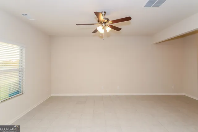 an empty room with a window and a fan