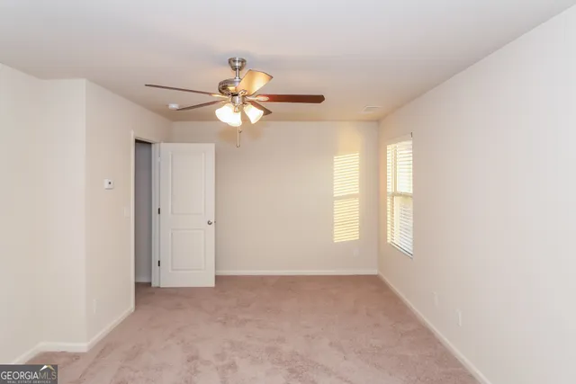 an empty room with windows and chandelier fan