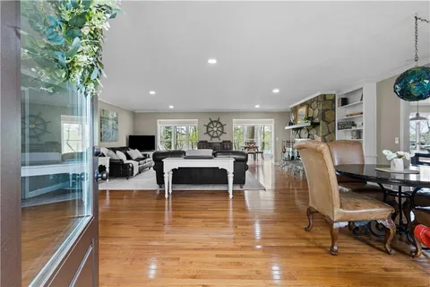 a kitchen with stainless steel appliances kitchen island granite countertop a sink dishwasher stove and white cabinets with wooden floor