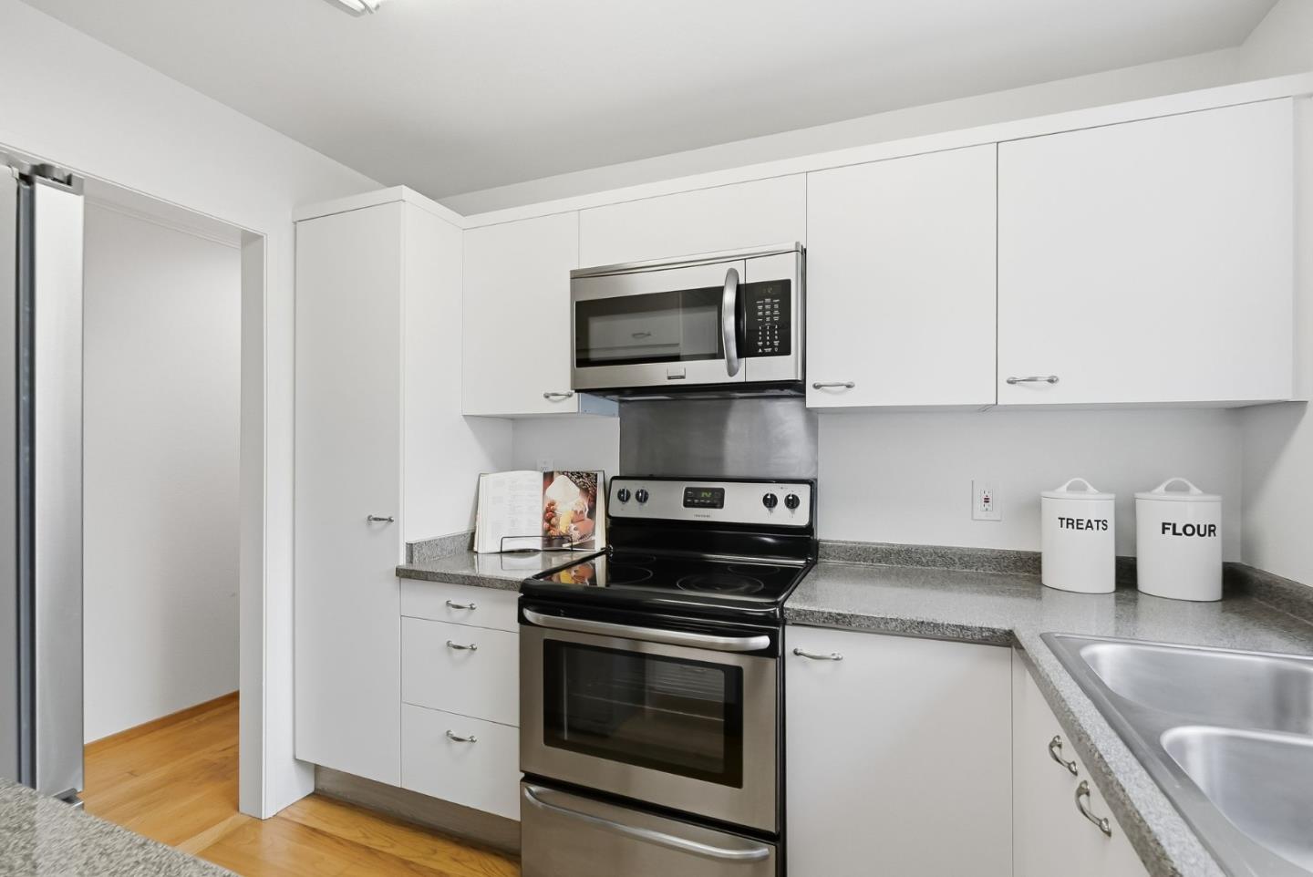 181 Ada Avenue, Unit 29 Mountain View, CA 94043 - Photo 10 of 30 a kitchen with stainless steel appliances granite countertop white cabinets a microwave a sink and a counter