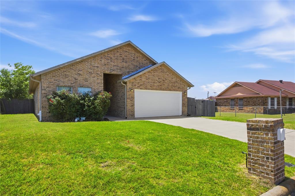 1502 Reed Street Greenville, TX 75401 - Photo 3 of 26 Brick exterior with a peaked roofline, an attached two-car garage, a concrete driveway, and a brick mailbox post