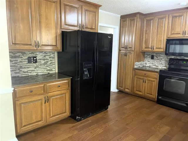 a kitchen with granite countertop stainless steel appliances a refrigerator and a stove top oven