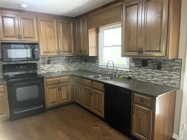 a kitchen with granite countertop stainless steel appliances wooden cabinets a sink and a window