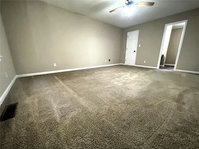an empty room with a chandelier fan and windows