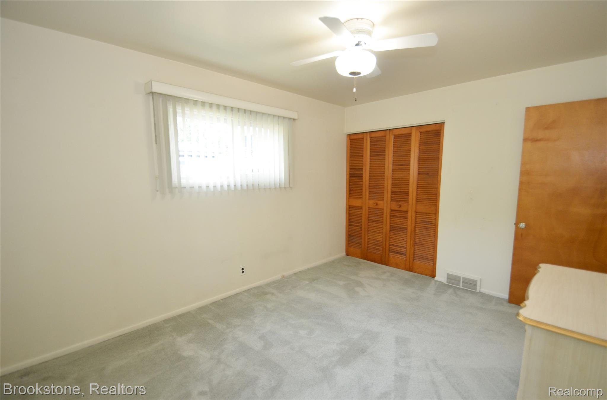 2822 Frembes Road Waterford, MI 48329 - Photo 12 of 25 Recessed window with horizontal blinds, overhead ceiling fan with lighting, light-toned carpet flooring, wood-finish bi-fold closet doors, and a wood-finish interior door
