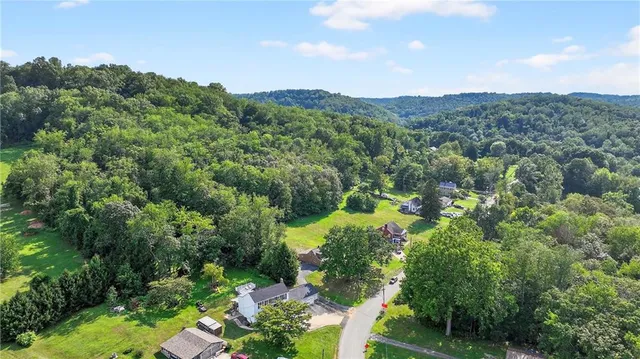 a view of a house with a street and a forest