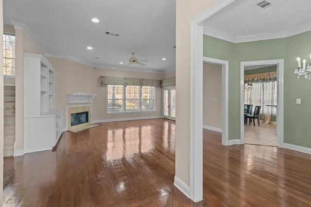 a view of an empty room with window and wooden floor