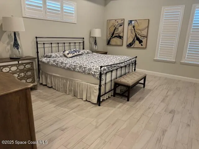 a bedroom with a bed a dresser and potted plants on the wooden floor