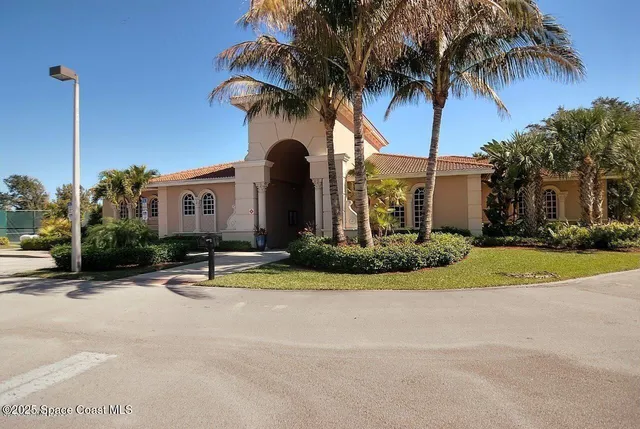 a view of a house with a yard and palm trees