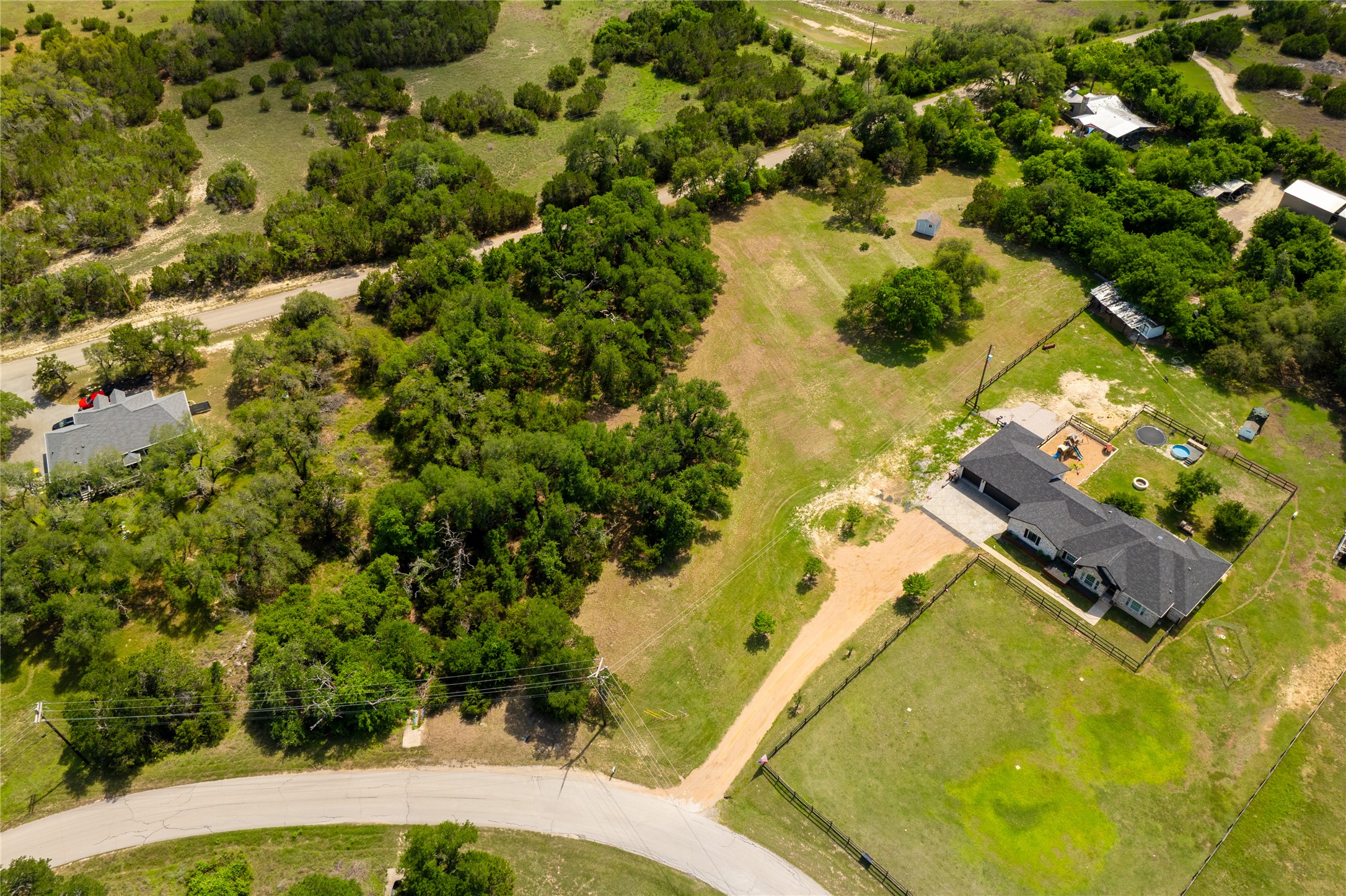 187 Beauchamp Road Dripping Springs, TX 78620 - Photo 13 of 19 Expansive property featuring a single-story residence with a black roof, a gravel driveway, and a fenced backyard