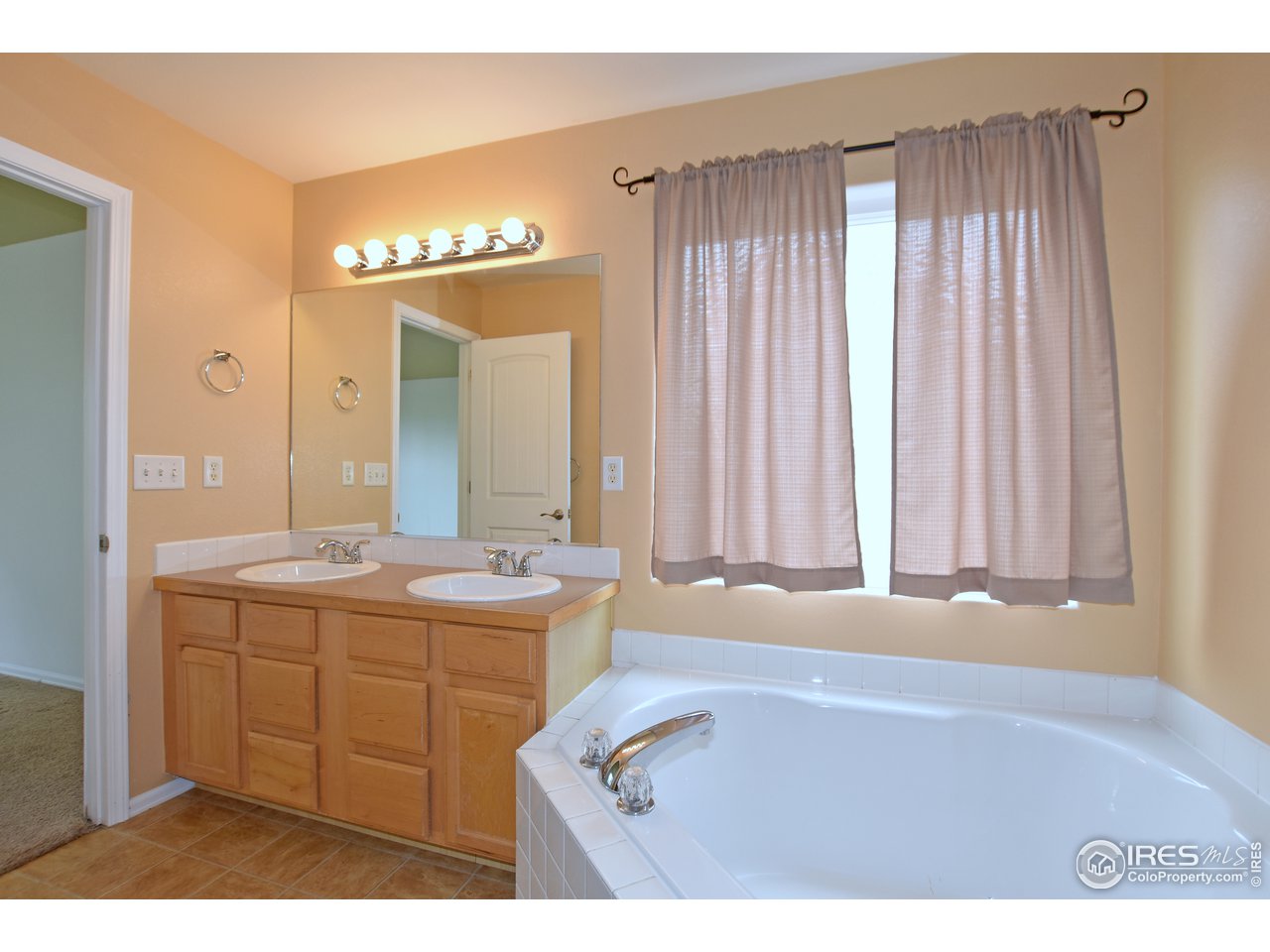 924 Cliffrose Way Severance, CO 80550 - Photo 27 of 40 a bathroom with a double vanity sink a mirror and a bathtub