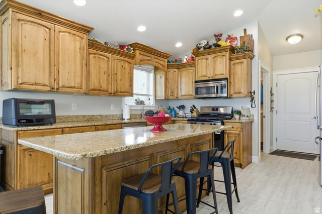 772 East 600 South Preston, ID 83263 - Photo 9 of 35 Kitchen featuring knotty wood cabinetry, granite countertops, stainless steel appliances, a center island with bar seating, and recessed lighting