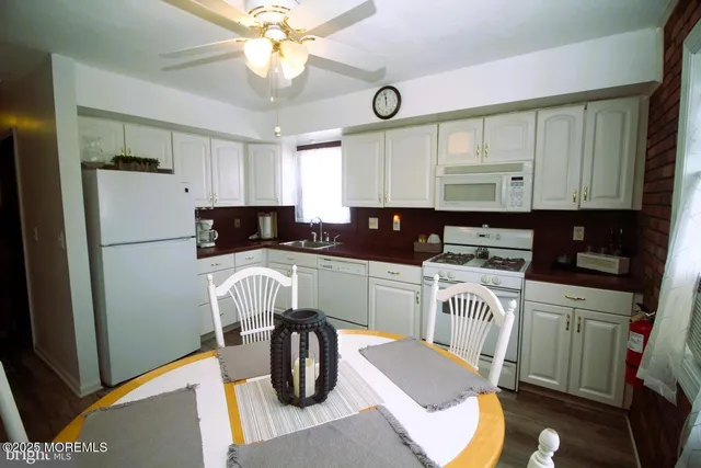 a kitchen with stainless steel appliances granite countertop a refrigerator a stove a sink dishwasher and a dining table with wooden floor