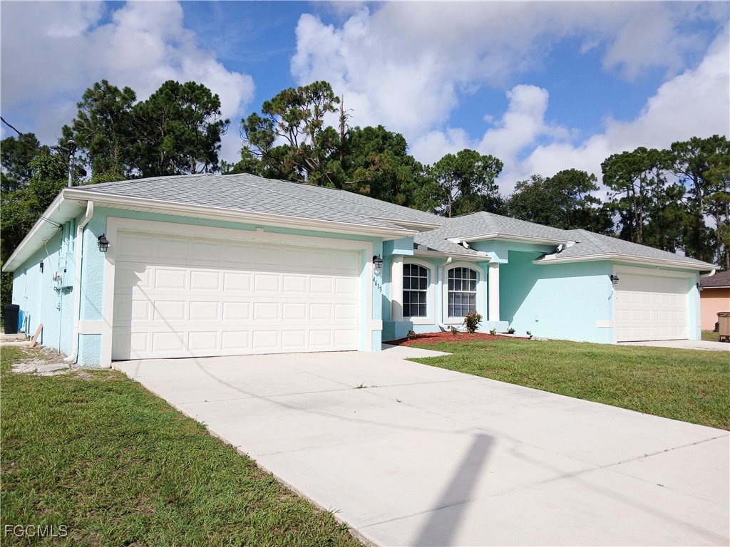 4613-4615 29th Street Southwest Lehigh Acres, FL 33973 - Photo 1 of 33 a front view of a house with a yard and garage