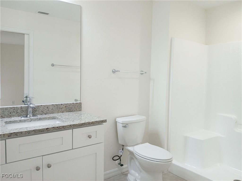 4613-4615 29th Street Southwest Lehigh Acres, FL 33973 - Photo 16 of 33 a bathroom with a granite countertop toilet a sink and a mirror