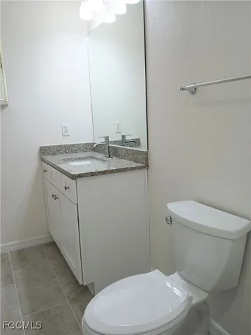 a bathroom with a granite countertop toilet and a sink