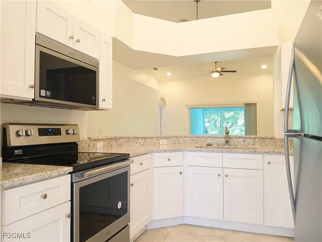 a kitchen with granite countertop white cabinets and white appliances