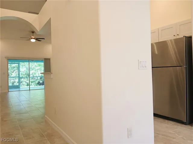 a view of a refrigerator in kitchen and an empty room