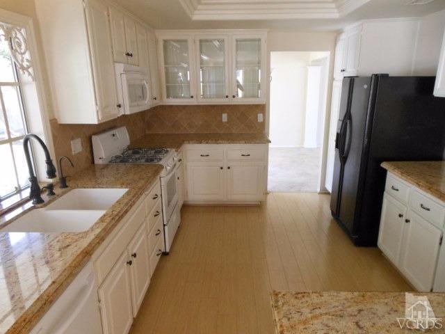 2287 Birchfield Street Simi Valley, CA 93065 - Photo 8 of 22 a kitchen with granite countertop a refrigerator a sink and white cabinets