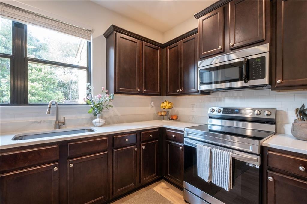 3950 Cyrus Crest Circle Northwest Kennesaw, GA 30152 - Photo 7 of 44 a kitchen with stainless steel appliances a sink a stove a microwave cabinets and a window