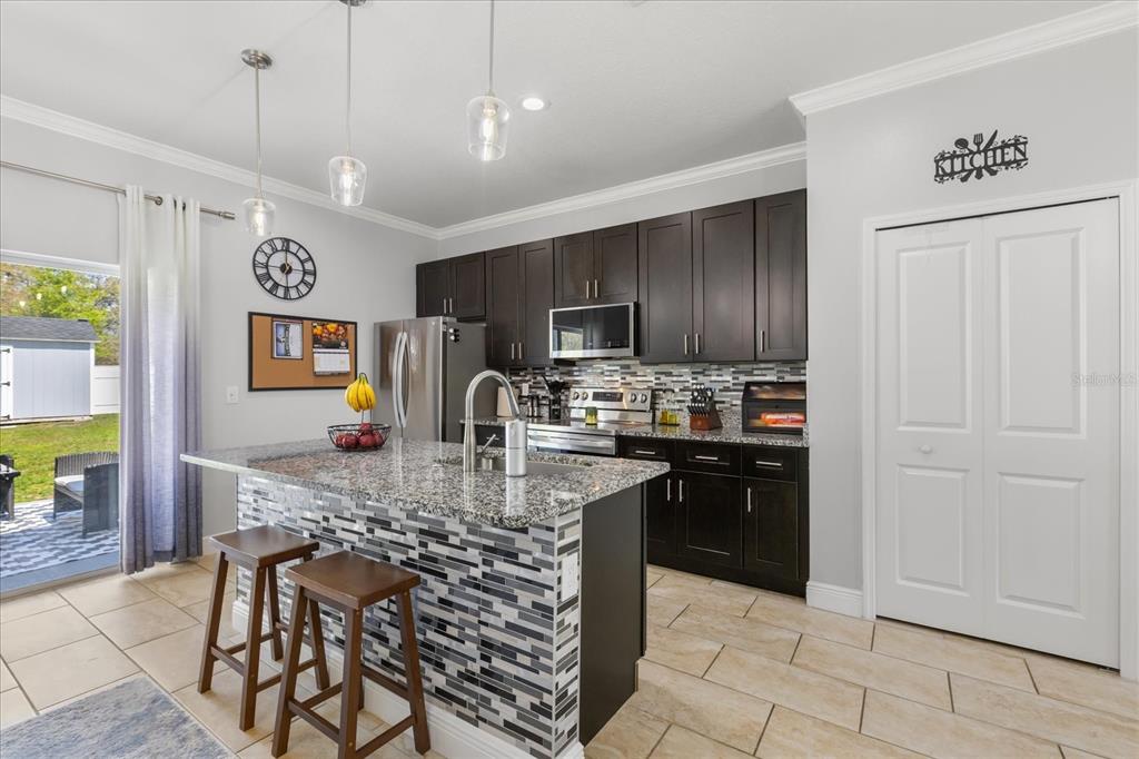 13657 Southwest 33rd Circle Ocala, FL 34473 - Photo 3 of 26 a kitchen with stainless steel appliances granite countertop a stove top oven a sink dishwasher a dining table and chairs with wooden floor