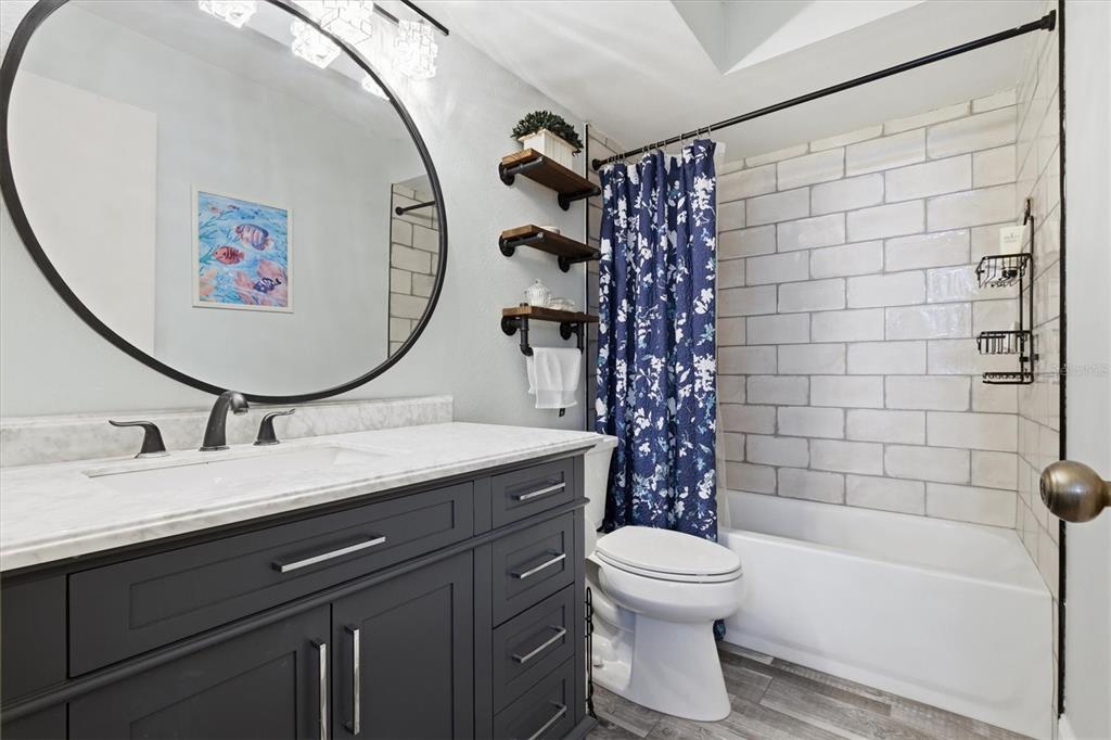 2178 Elm Street, Unit 1007 Dunedin, FL 34698 - Photo 25 of 28 a bathroom with a granite countertop sink toilet a mirror and shower