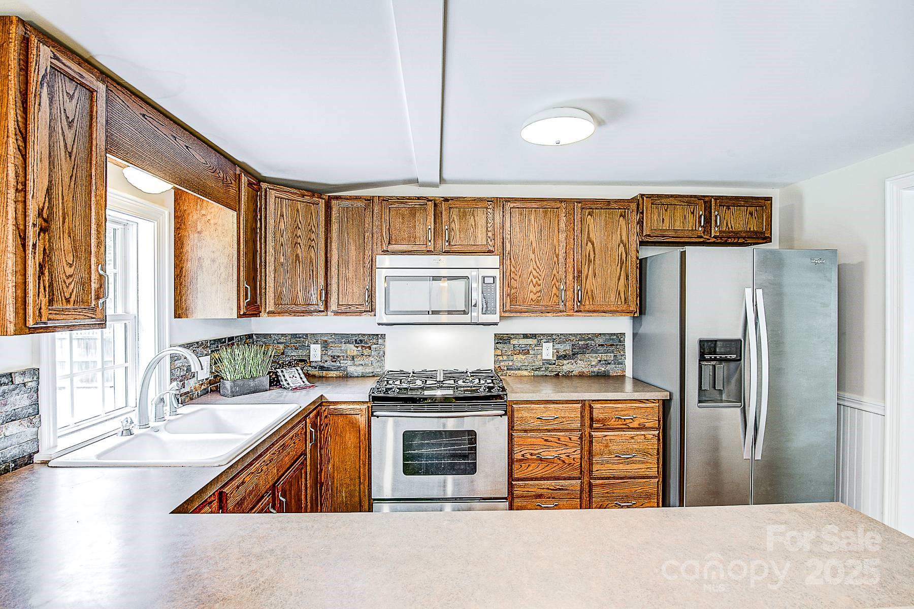5165 Woodleaf Road Salisbury, NC 28147 - Photo 16 of 48 a kitchen with granite countertop a stove a refrigerator and a sink