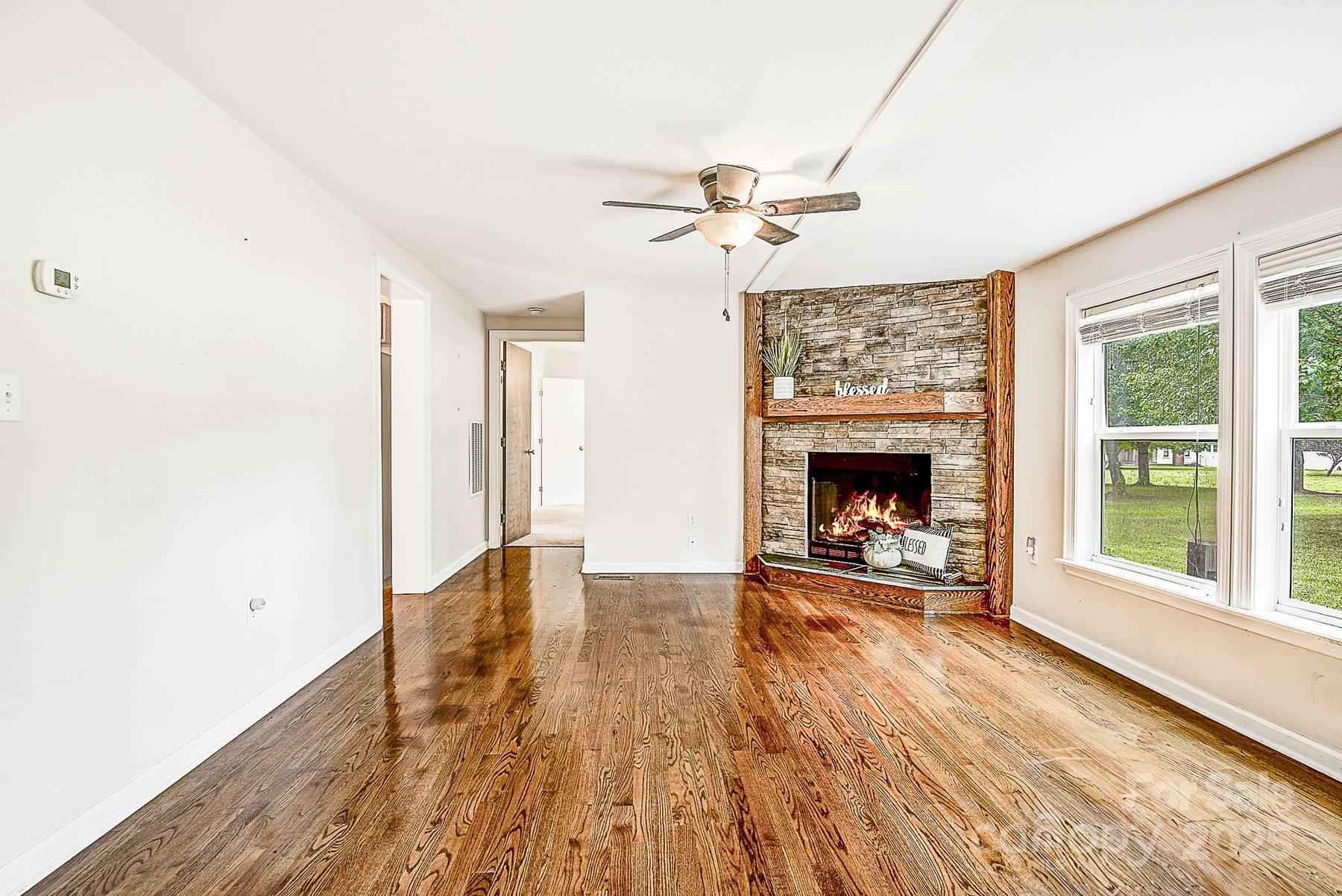 5165 Woodleaf Road Salisbury, NC 28147 - Photo 5 of 48 a view of a livingroom with wooden floor a fireplace and windows