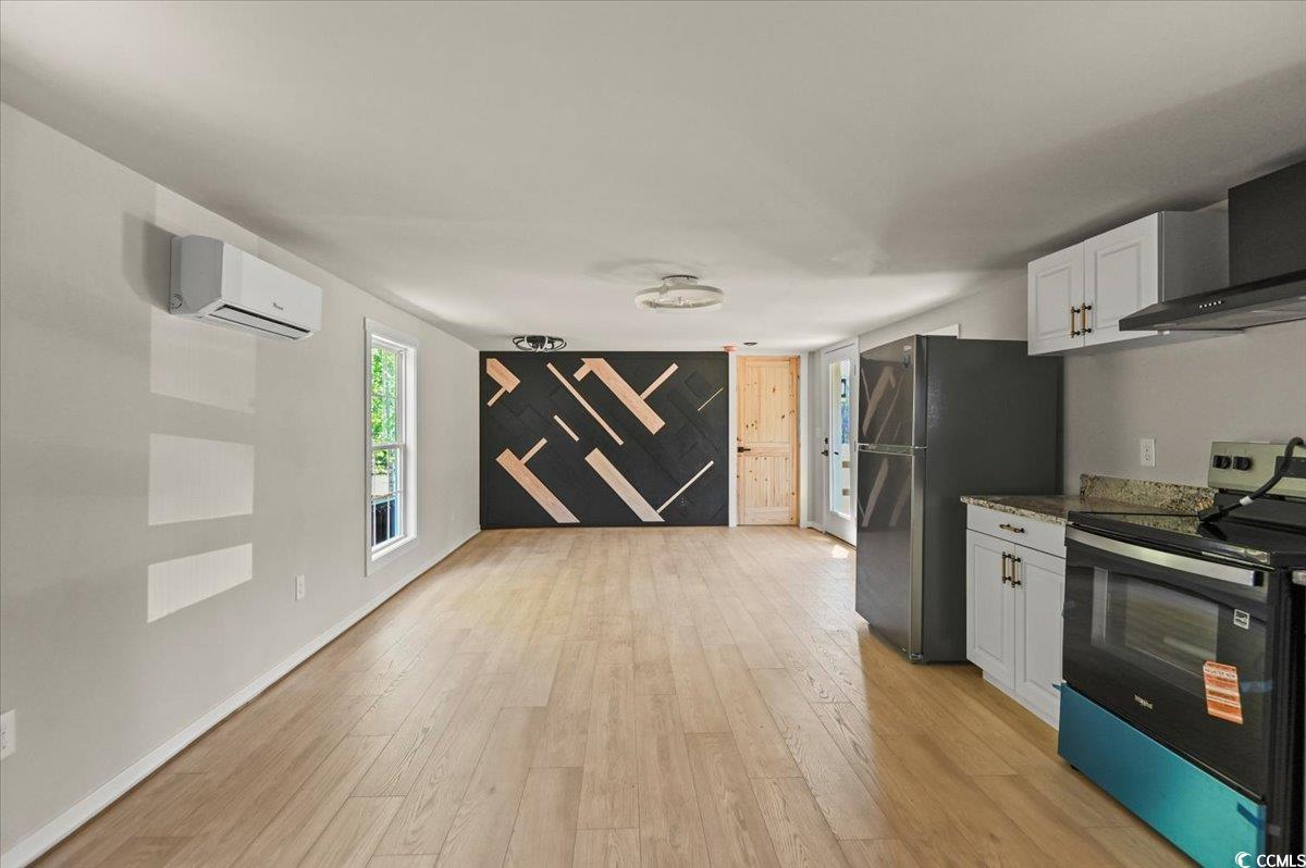 446 Sonny Road Gresham, SC 29546 - Photo 8 of 40 Kitchen with an AC wall unit, black range with electric cooktop, light wood-style flooring, white cabinets, and freestanding refrigerator