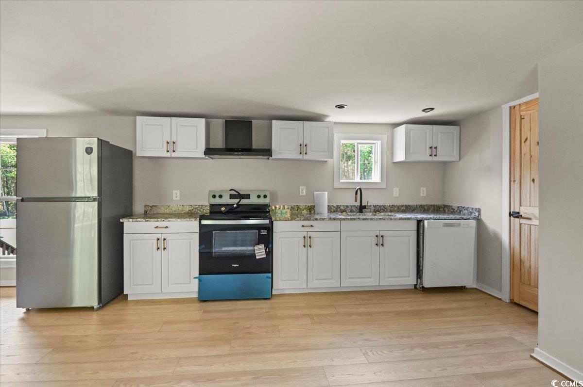 446 Sonny Road Gresham, SC 29546 - Photo 9 of 40 Kitchen with wall chimney exhaust hood, stainless steel appliances, a wealth of natural light, and light wood-type flooring
