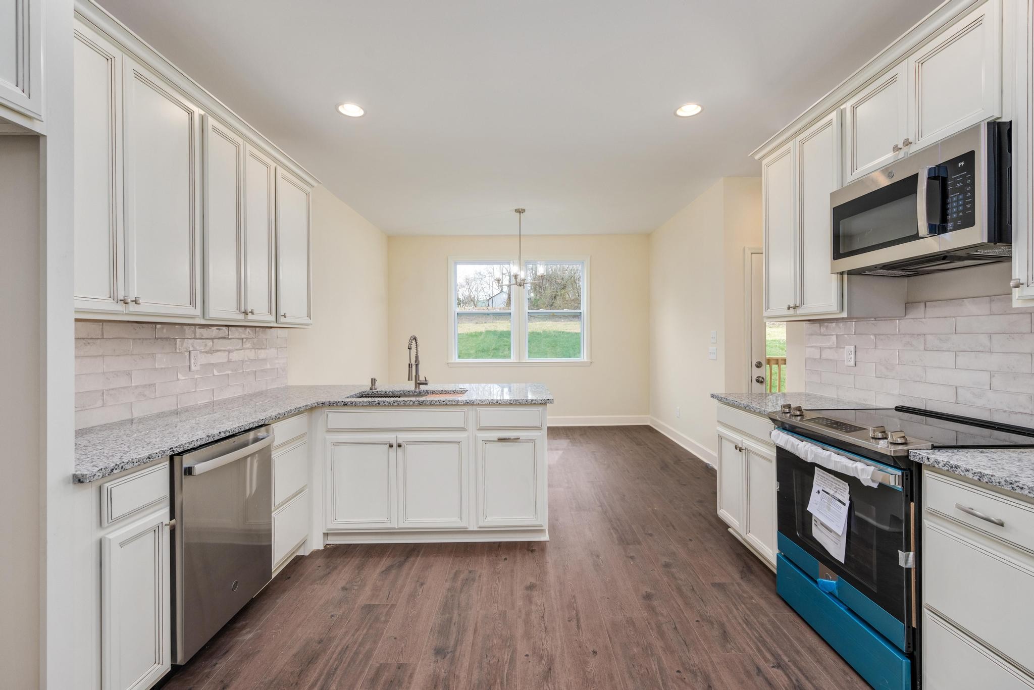 157 Lena Loop Burns, TN 37029 - Photo 13 of 49 a kitchen with stainless steel appliances granite countertop wooden cabinets a sink a stove a microwave and wooden floors