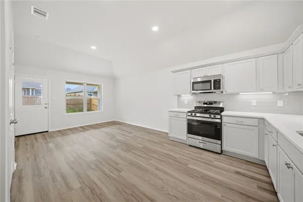 a kitchen with granite countertop a stove a sink and a refrigerator