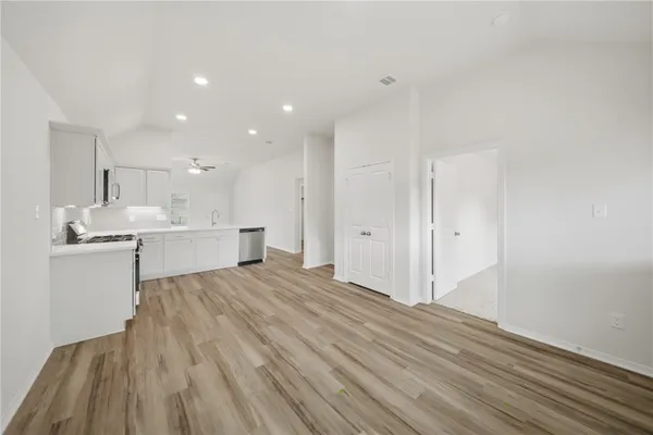 a view of kitchen and empty room with wooden floor