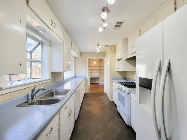 a kitchen with stainless steel appliances a sink a stove a refrigerator cabinets and a window