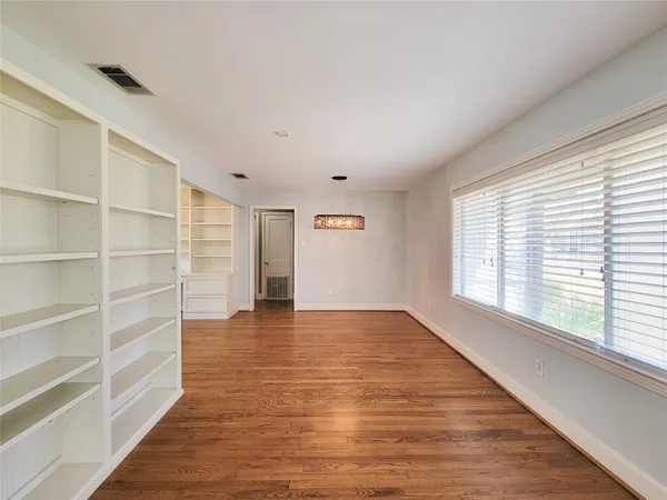a view of an empty room with a window and wooden floor