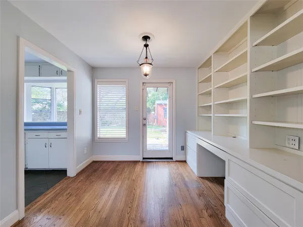 a view of an empty room with a window and wooden floor