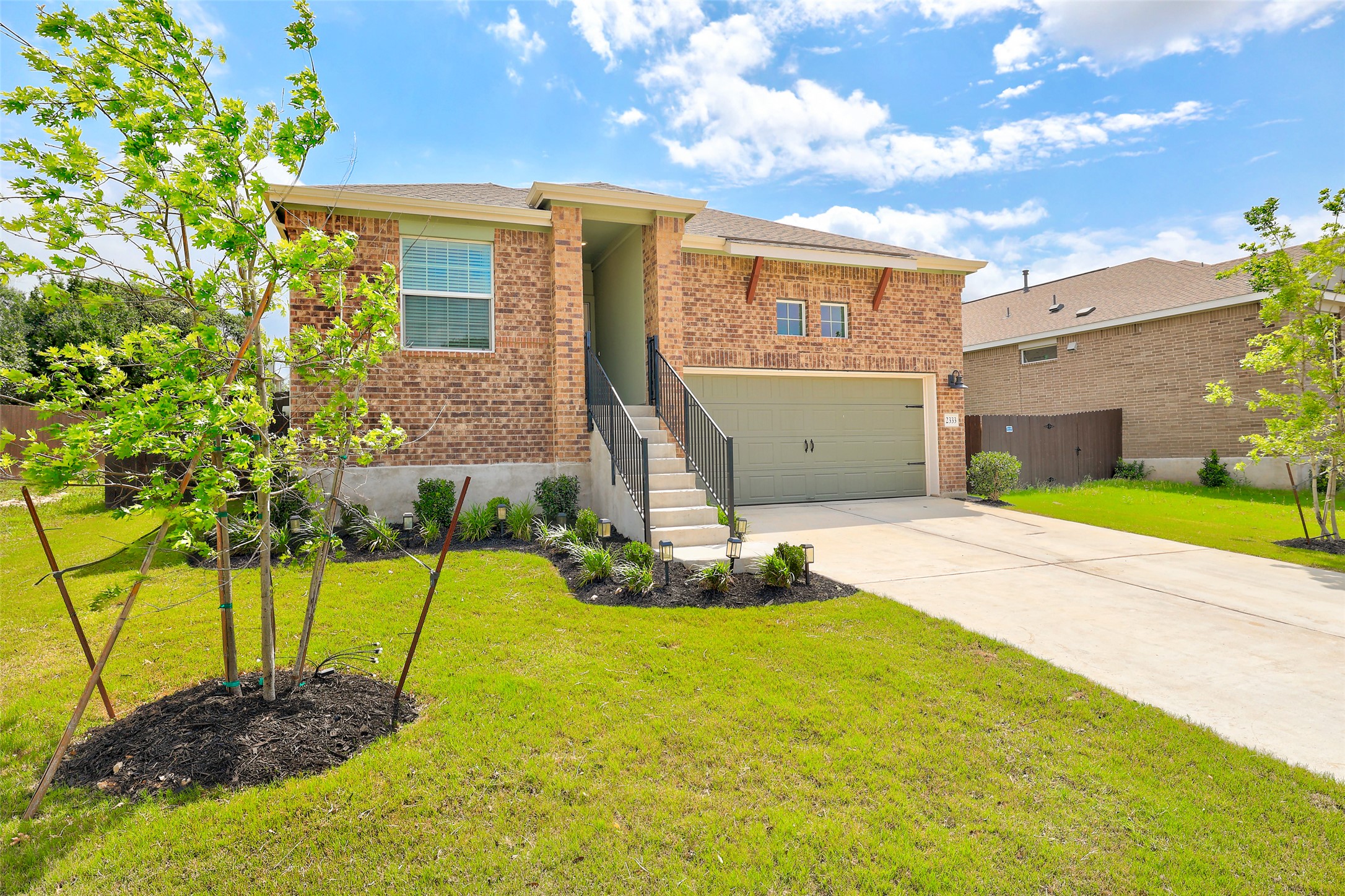 2333 Four Waters Loop Georgetown, TX 78628 - Photo 2 of 35 Brick facade residence featuring a two-car garage, concrete driveway, and front stairs with metal railings