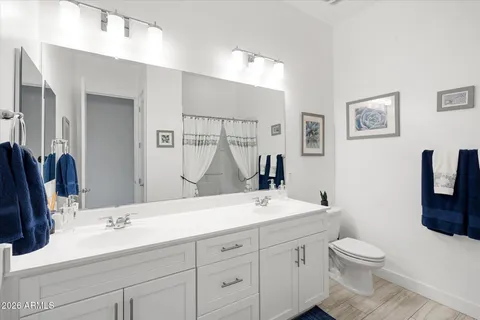 a bathroom with a toilet a double vanity sink and a mirror