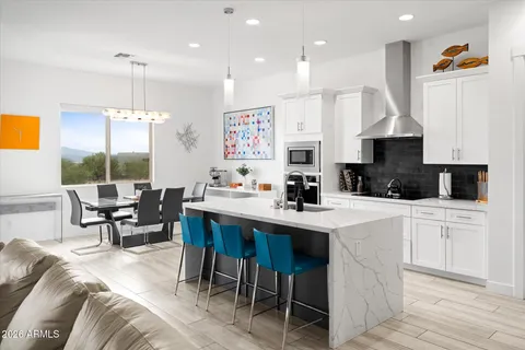 a kitchen with stainless steel appliances granite countertop a table chairs a sink dishwasher a microwave oven and a dining table with wooden floor