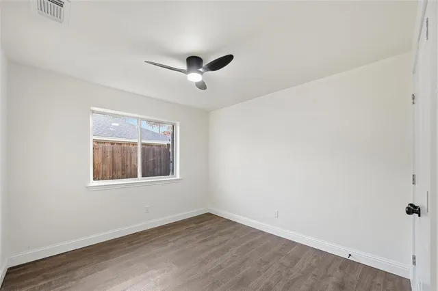 an empty room with wooden floor ceiling fan and windows