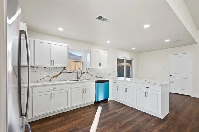 a kitchen with white cabinets appliances and wooden floor