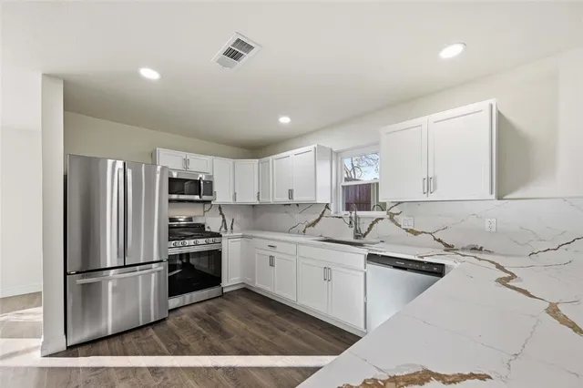 a kitchen with stainless steel appliances granite countertop a sink stove and refrigerator