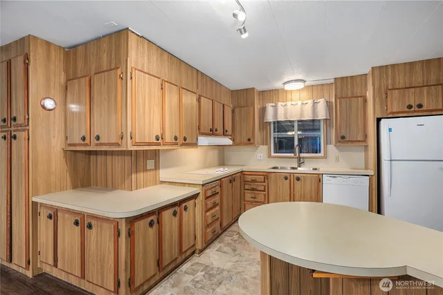 a kitchen with kitchen island a sink a stove a refrigerator and cabinets